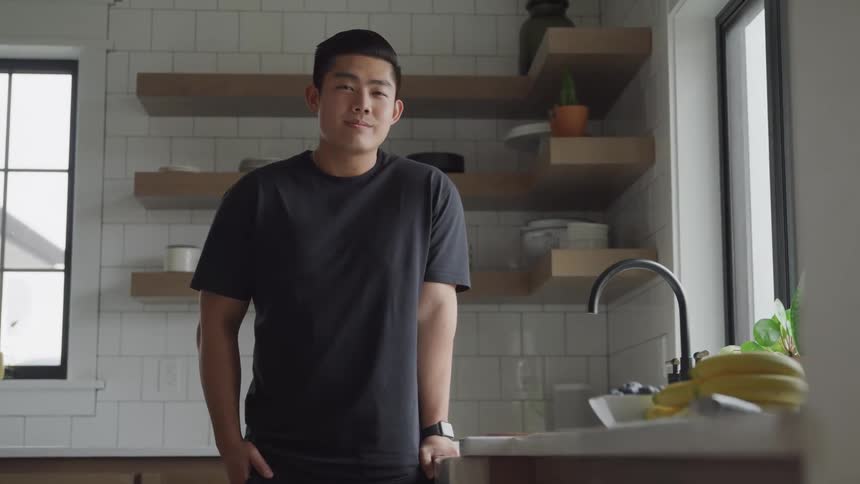Man in black tshirt in kitchen next to sink