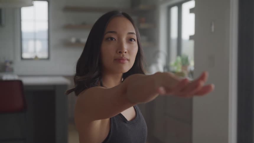 An asian woman is stretching and doing yoga indoors