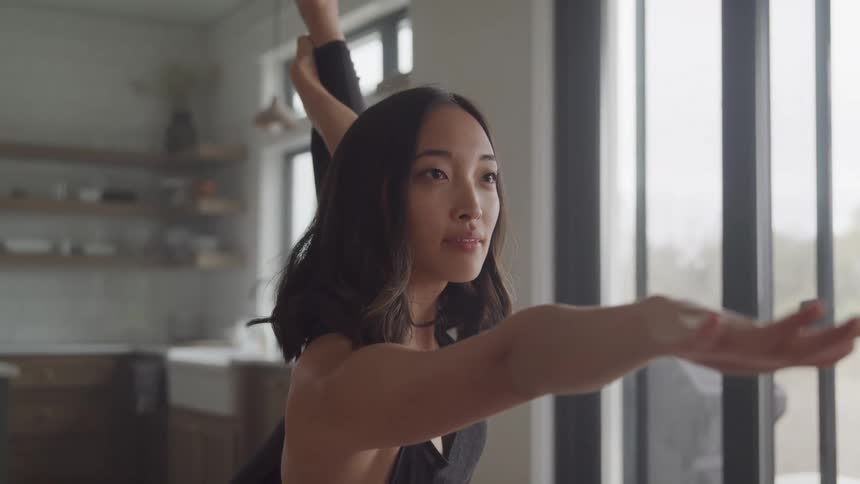 A woman is doing yoga and holding her leg up