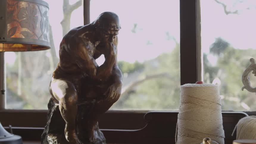 Statue of man sitting and resting his chin on his fist
