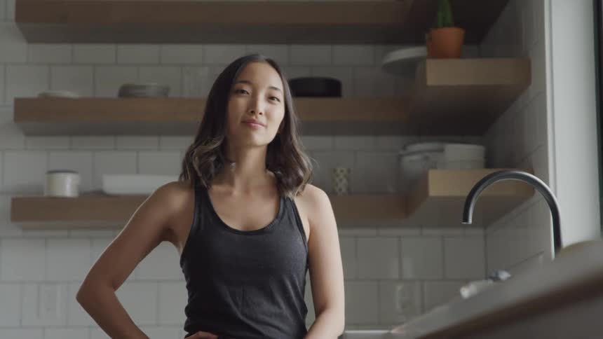 Young woman in kitchen with hand on waist