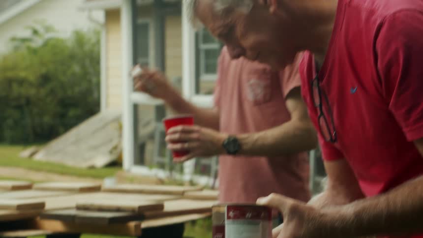Two men varnishing a wooden object