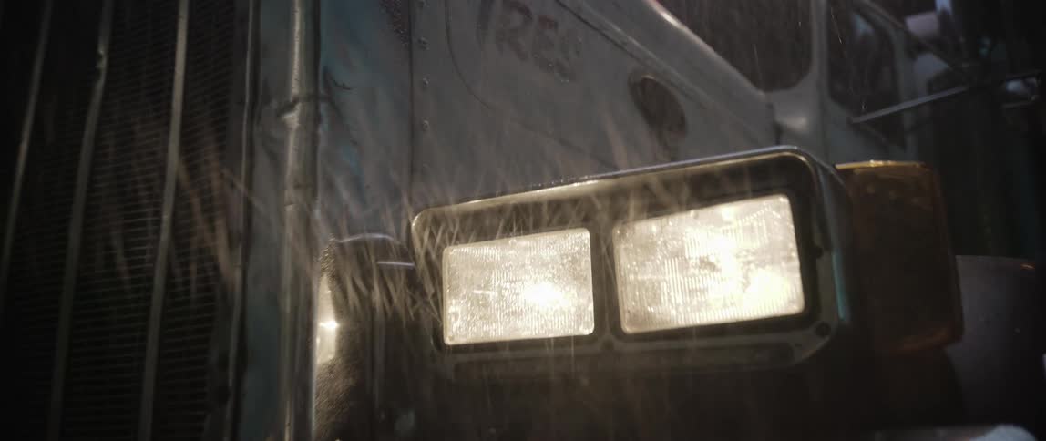 Truck with headlights on stopped in the rain