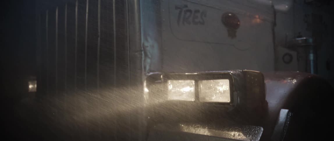 Heavy rain pours on the headlight of the truck