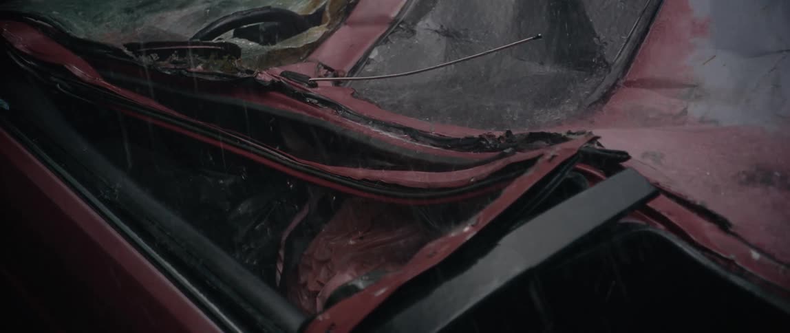 Heavy rainfall falls on the trashed car