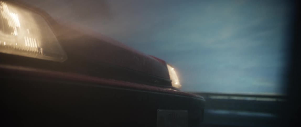 Red vehicle with headlights on driving on a rainy day