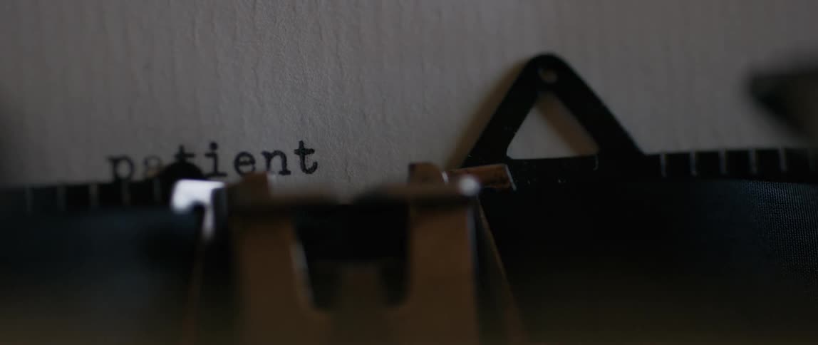 Typing patient on an old school manual typewriter on a white sheet of a paper