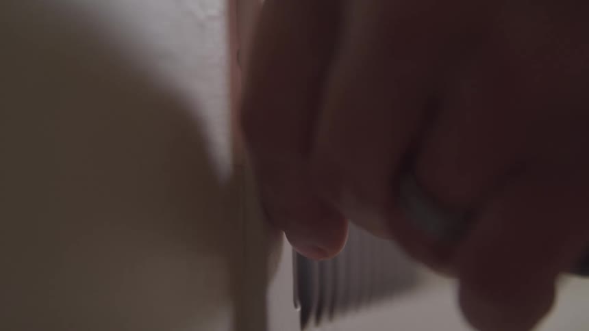 Hand removing a screw from a wall