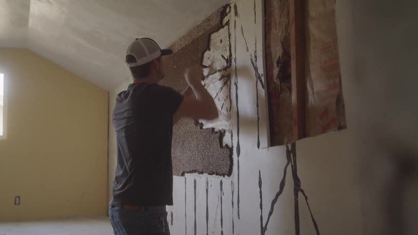 Carpenter removing brown chunks from a wall