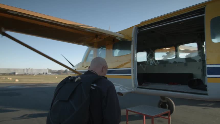 Man with backpack walking and getting into small airplane
