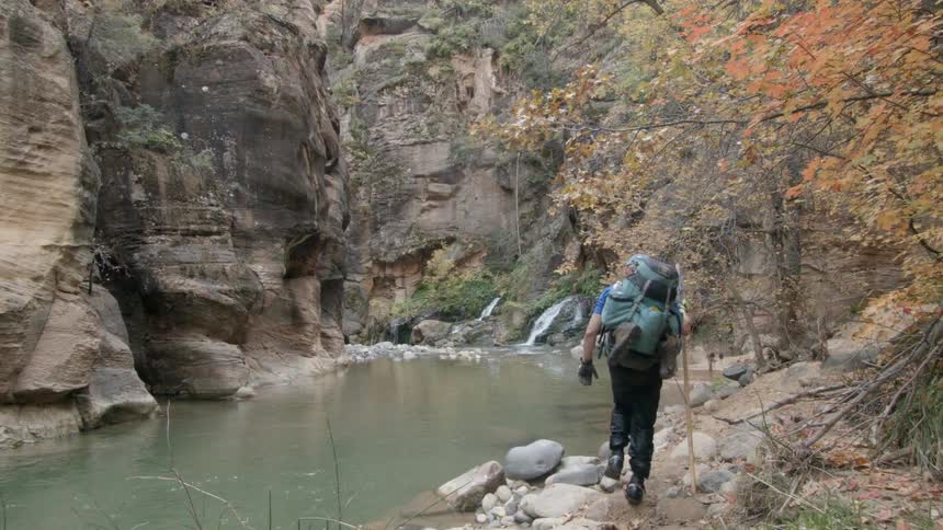 A man is hiking along the rocks of this pond