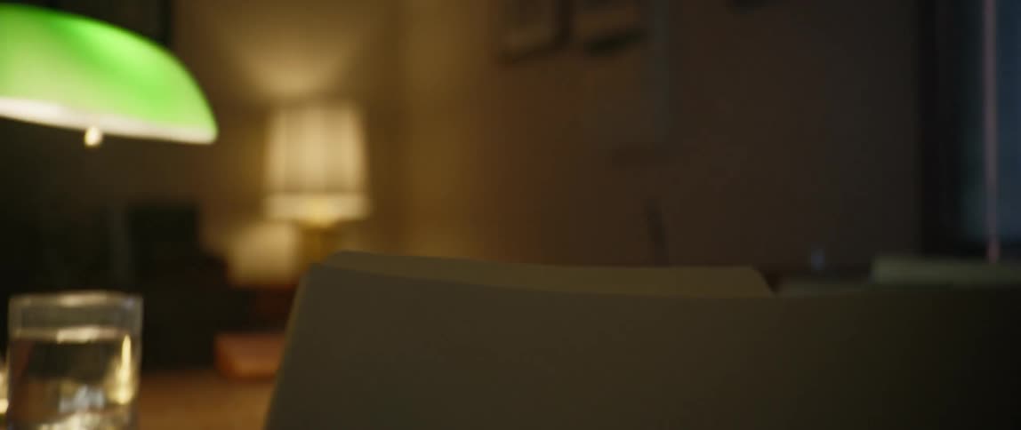 A person opens a folder at a desk and briefly reads the notes inside of it