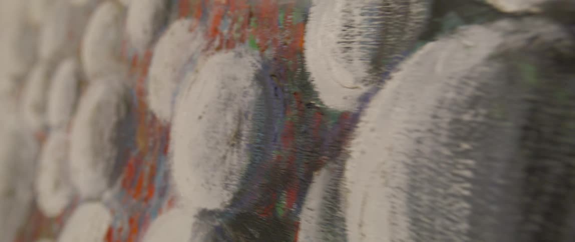 Close up of a painting of white spheres on a dark orange green and light blue background