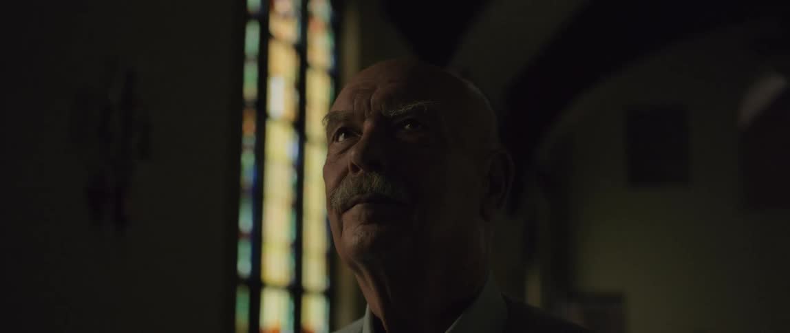 An elderly man is standing inside a church by himself