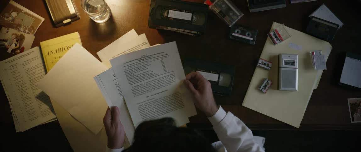 A man is sorting through paperwork as he sits at a desk at night