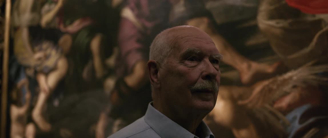 An elderly man looking around while standing in a museum