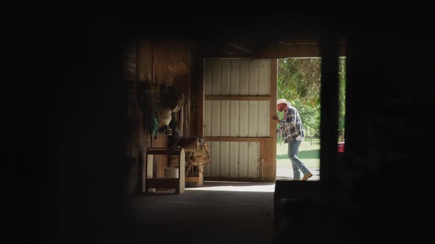 A man opens the sliding door of a barn