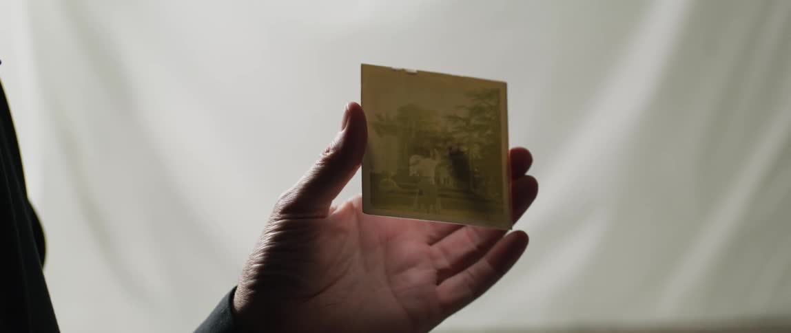 A person holds an old photograph in their hand