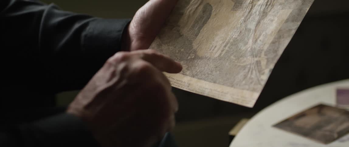 A mans hand pointing to a drawing on a piece of paper resting on his left arm
