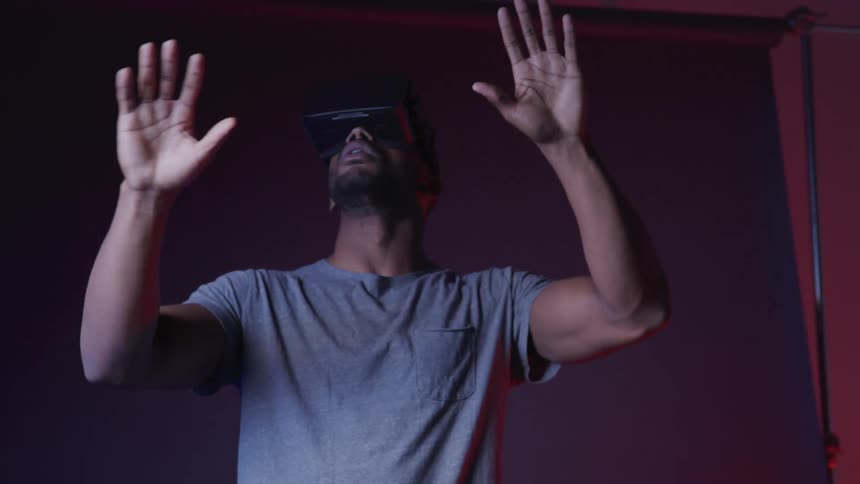 A man wearing a vr headset moves his arms and hands