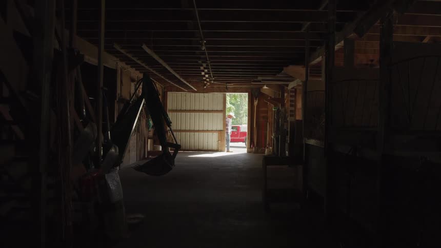A man pulls and closes the door of a garage from outside during the day