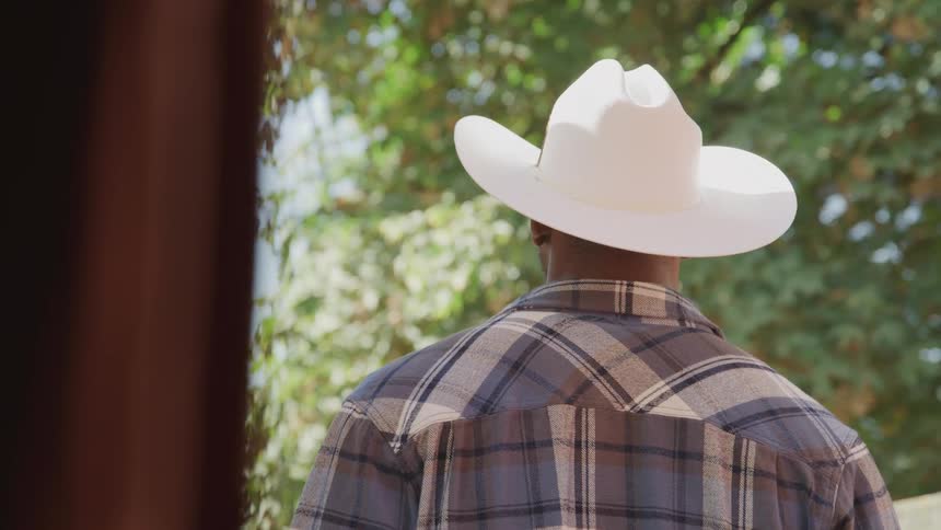 A cowboy is standing outside a barn