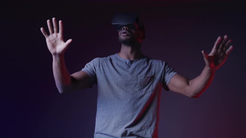 A man moves his hands around while using a virtual reality headset