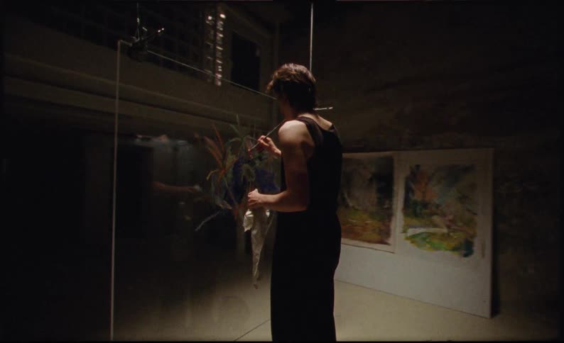 A woman is painting on a sheet of glass