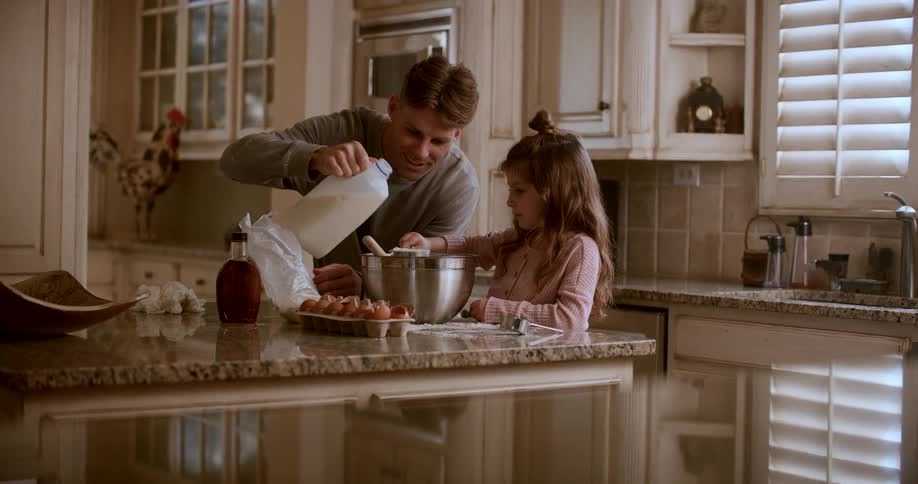 A man pours milk in a bowl and a girl mixes it