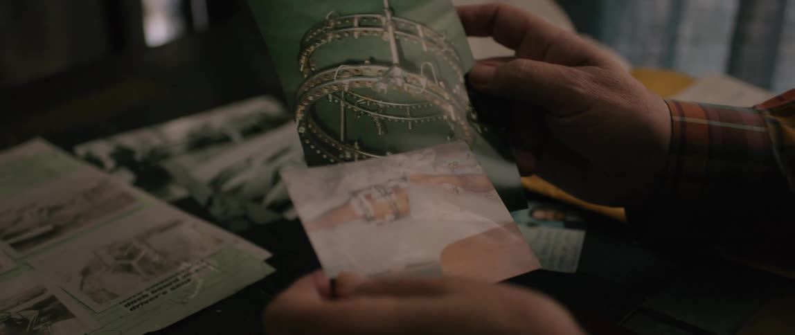 A man is holding two photographs pointing out certain similarities