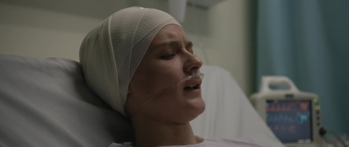 A sick woman speaks and turns her head away while lying on a hospital bed