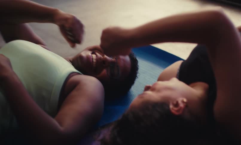 Two friends lay down after exercising and fist bump