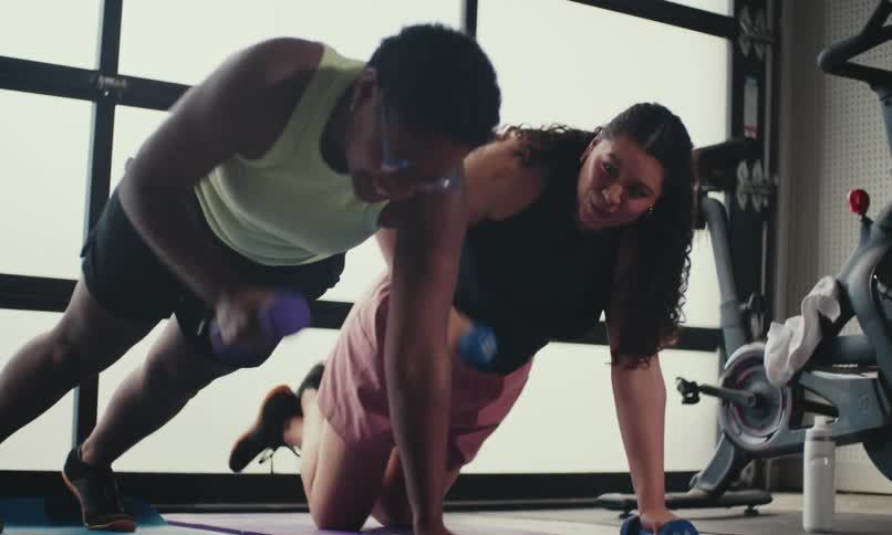 Two women in a gym doing physical exercise with dumbbells