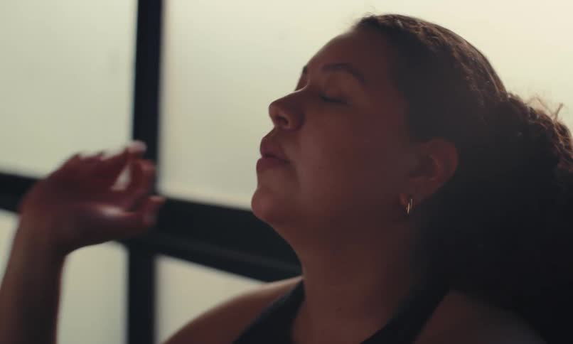 A woman who is breathing hard uses her hand to wipe sweat off her head