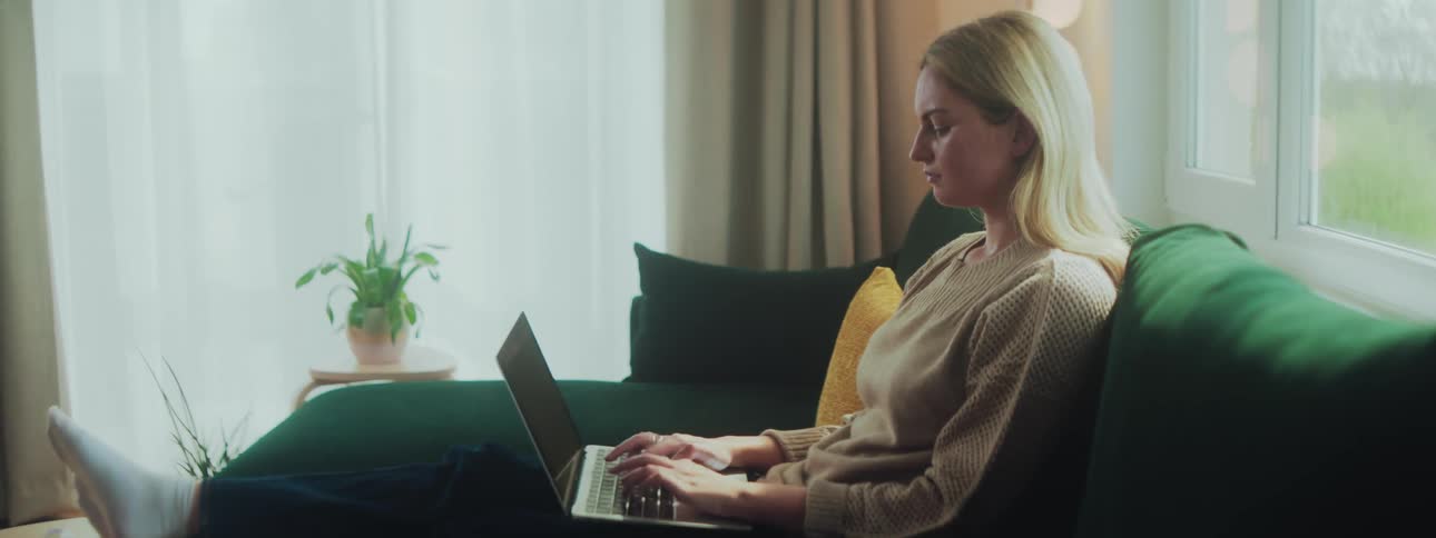 A woman is at home typing on her laptop