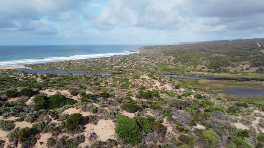 Aerial landscape of a mountain valley with sparse vegetation and a beach in the background