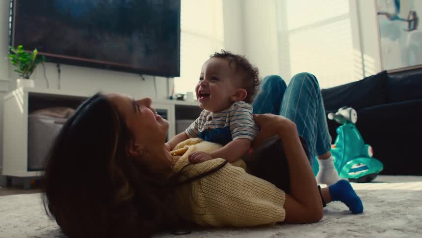 Mother lying on the living room rug playing with her son