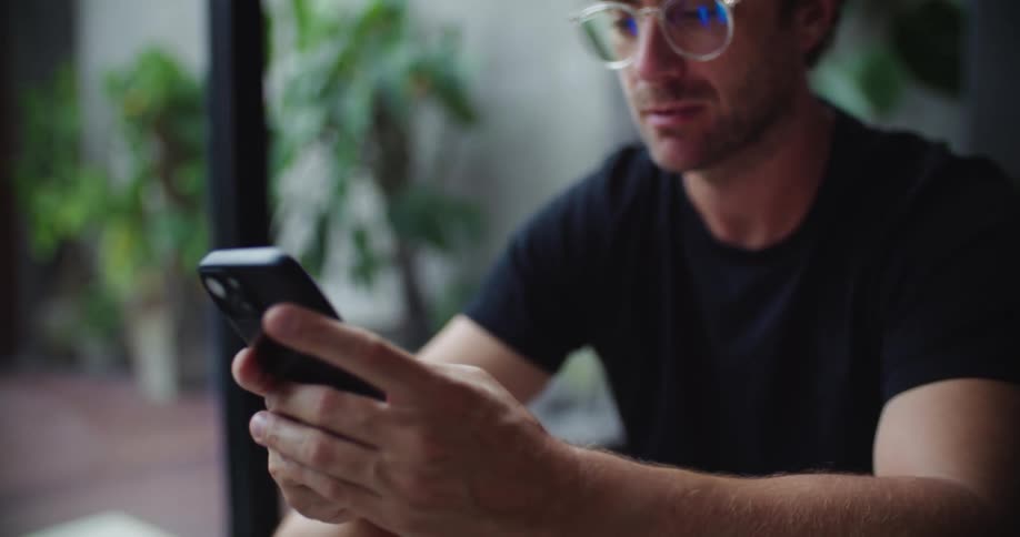 A man sits texting by the window