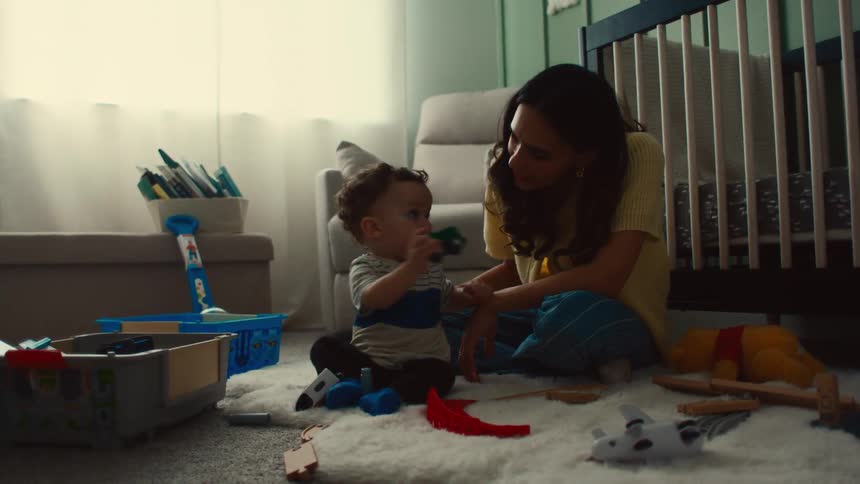 Mother and infant son playing with toys on the bedroom floor
