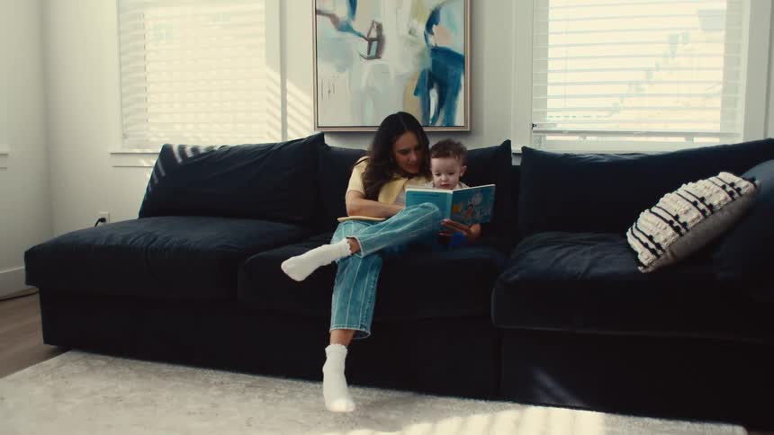 A mother telling a story to her baby on the couch