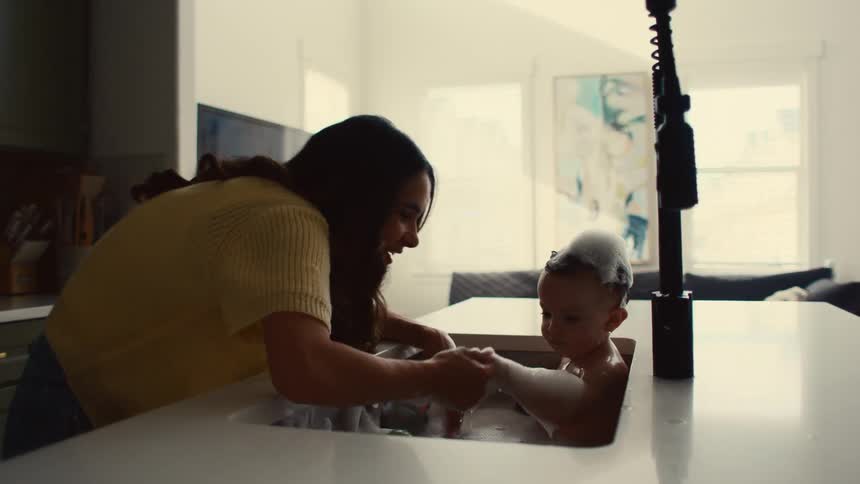 Mother bathing her son in the sink