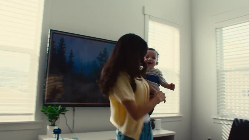 A woman carries a baby on her side as she spins and dances
