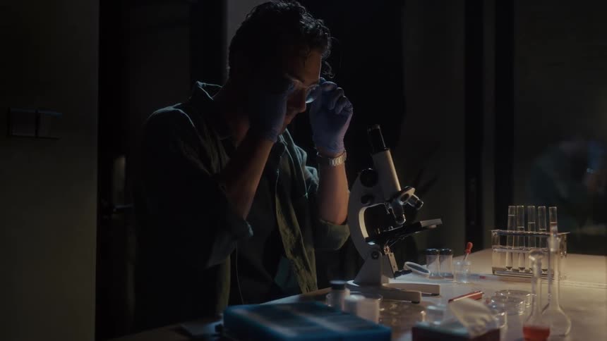 A scientist is working using a microscope and test tubes