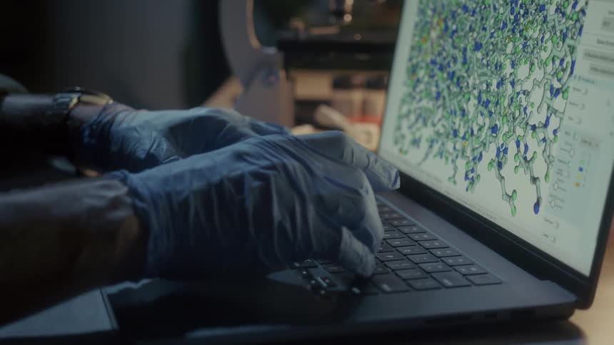 A scientist is typing on a laptop in the lab