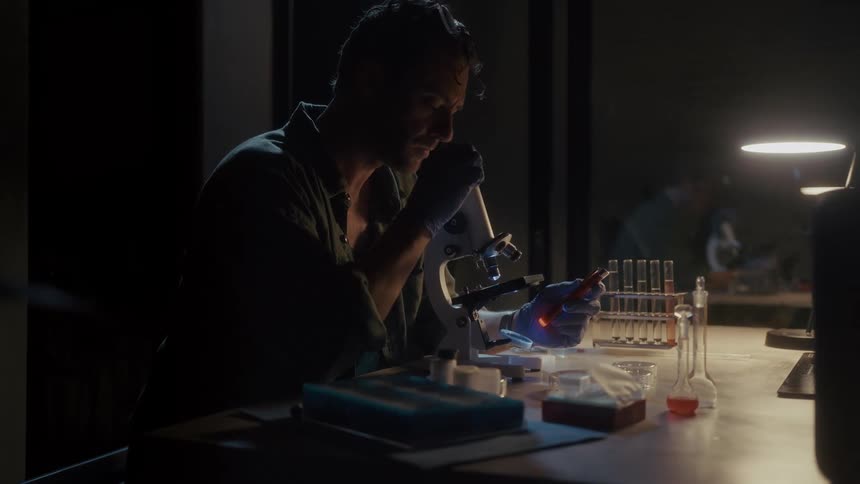 A scientist is examining a specimen in the microscope