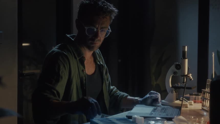 A scientist is working at night going through microscope slides