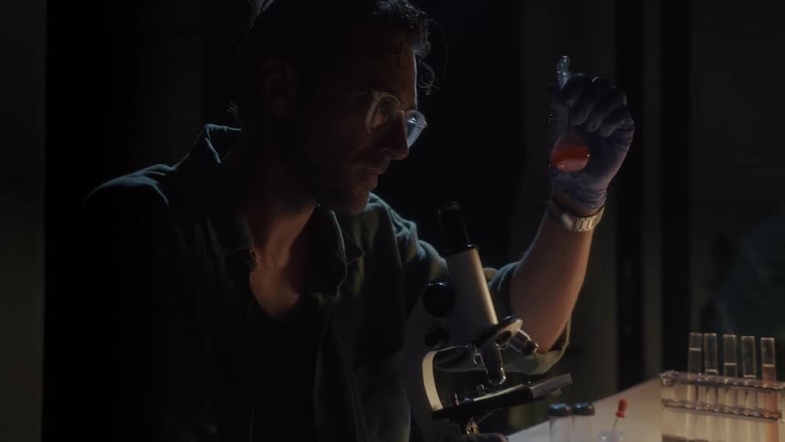 A man in a laboratory analyzing samples in a flat bottom flask
