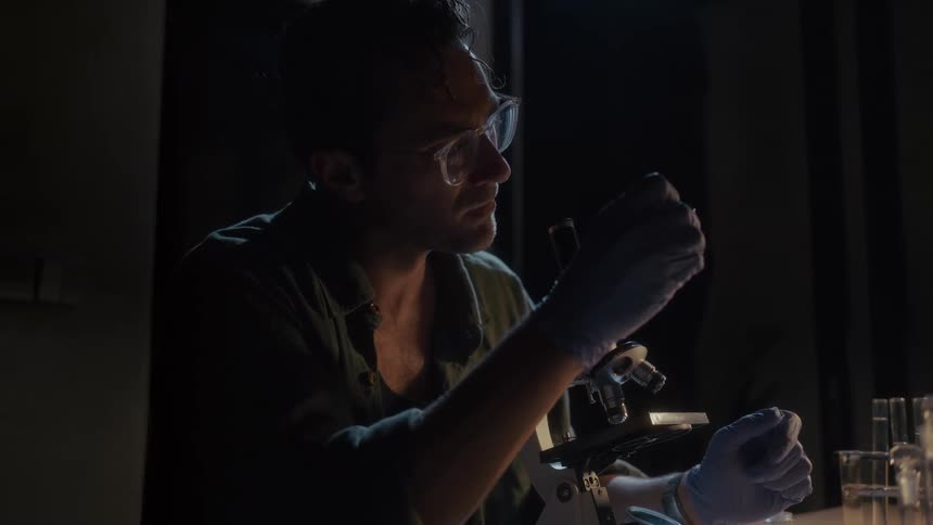 A scientist is examining microscope slides in the lab