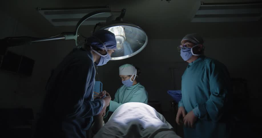 A doctor is giving chest compressions during an emergency in the operating room