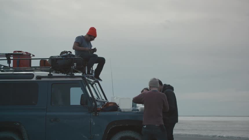 Men eating lunch on a car hood in the desert